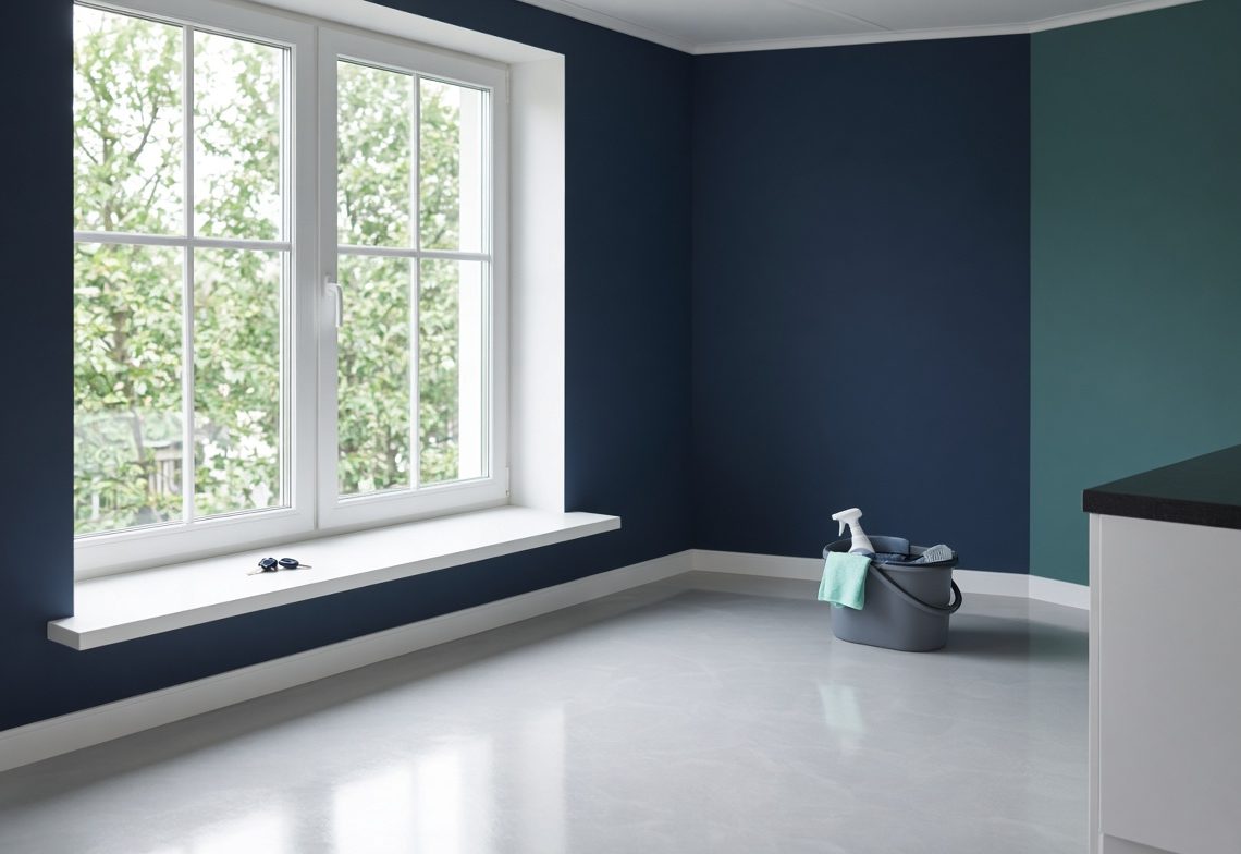A freshly cleaned empty room with polished floors and a cleaning bucket